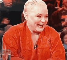 a woman in a red shirt is laughing in front of a crowd of people .
