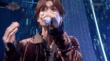a man is singing into a microphone while wearing a glove