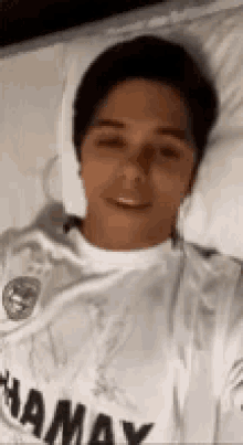a man in a white shirt is laying on a bed with his eyes closed .