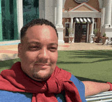 a man with a red scarf around his neck sits in front of a building that says sierra nevada on it