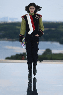 a model walks down the runway at a fashion show wearing a jacket with a cross on it