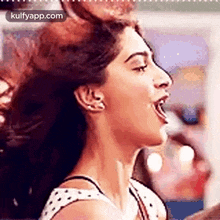 a close up of a woman 's face with her mouth open and her hair in the air .