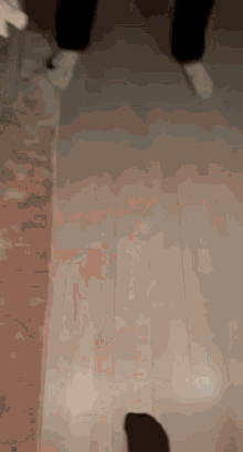 a blurred image of a person 's feet walking on a wooden floor