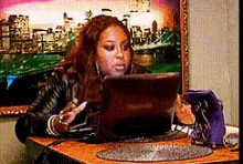 a woman sitting at a table with a laptop and a phone
