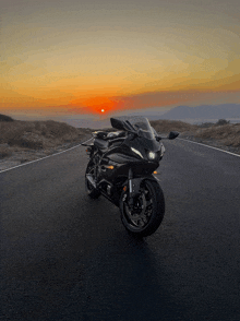 a black motorcycle is parked on a road at sunset