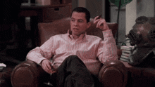 a man in a striped shirt is sitting in a chair smoking a cigar