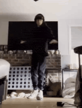 a man is dancing in a living room in front of a flat screen tv .