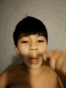 a shirtless young boy is making a funny face with his mouth open