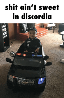 a little boy in a swat costume is sitting in a toy police car