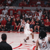 a basketball player with the number 21 on his jersey dribbles the ball