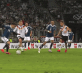 a group of soccer players are playing on a field with a wurth sign in the background