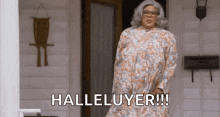 a woman in a floral dress is standing in front of a door and saying halleluyer .