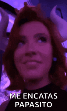 a woman with red hair and horns is wearing a purple wig and a black shirt .