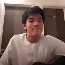 a man in a white shirt is playing a guitar