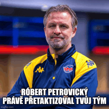 a man wearing a blue and yellow kappa jacket stands with his arms crossed