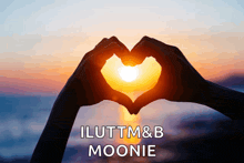 two hands making a heart shape with the sun behind them