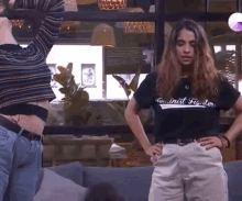 a man and a woman are standing next to each other in a room with their hands on their hips .