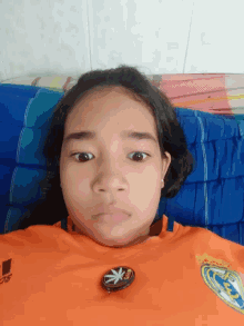 a girl wearing an orange shirt with the word adidas on the front
