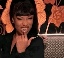 a woman in a black jacket is smiling and holding a spoon in her mouth