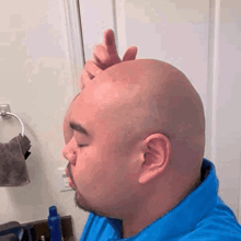 a man with a beard is shaving his head in front of a mirror in a bathroom .