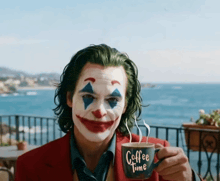 a man dressed as the joker is holding a cup of coffee