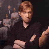 a man sitting with his arms crossed in front of a poster that says r