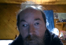 a man with a beard and a bald head looks at the camera