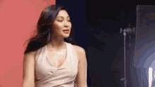 a woman in a white dress is standing in front of a red and blue wall in a studio .
