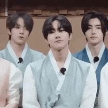 a group of young men wearing traditional clothes are standing next to each other in a room .