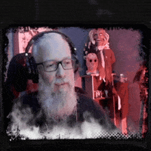 a man with a beard wearing headphones and glasses looks at the camera