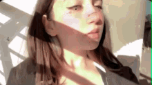 a close up of a woman 's face with the sun shining on her face .