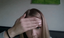 a woman covering her face with her hands while looking at the camera