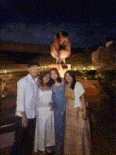 a group of people pose in front of a statue at night