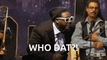 a man in a suit and tie stands in front of a microphone and says " who dat "