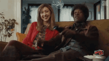 a man and a woman are sitting on a couch with a sign that says roach tea plus +
