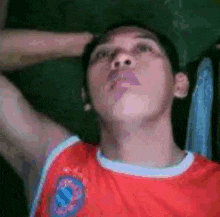 a man wearing a red shirt with a blue and white emblem on it