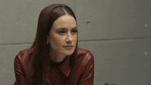 a woman wearing a red leather jacket is sitting at a table