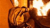 a person is sitting in front of a fire covering their face .