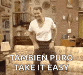 a man is dancing in front of a couch with the words tambien puro take it easy written below him .