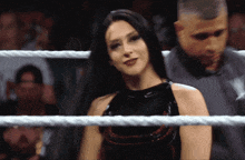 a woman in a black dress is standing in a ring