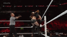 a female wrestler is being lifted in the air by another wrestler in a wrestling ring ..