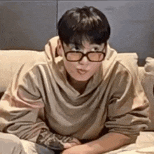 a man wearing glasses is sitting on a couch .