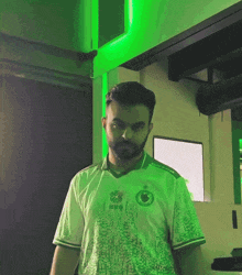 a man with a beard is wearing a white shirt with a green circle on it