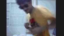 a man wearing sunglasses and a yellow shirt is dancing in front of a window