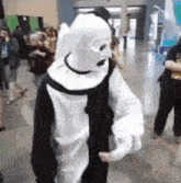 a person in a black and white clown costume is dancing in a crowd of people .
