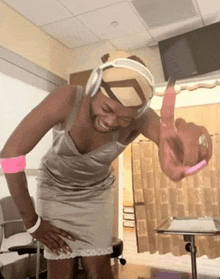 a man wearing headphones and a dress is standing in a hospital room .