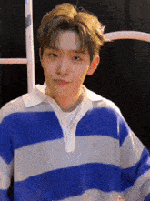 a young man wearing a blue and white striped sweater and a pearl necklace .