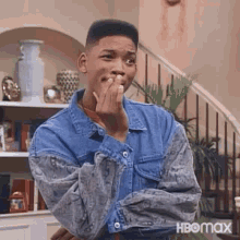 will smith is wearing a denim jacket and covering his mouth with his hands .
