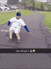 a man wearing a blue jays shirt is sliding down a road