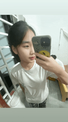 a girl taking a picture of herself with a phone that has a face on it